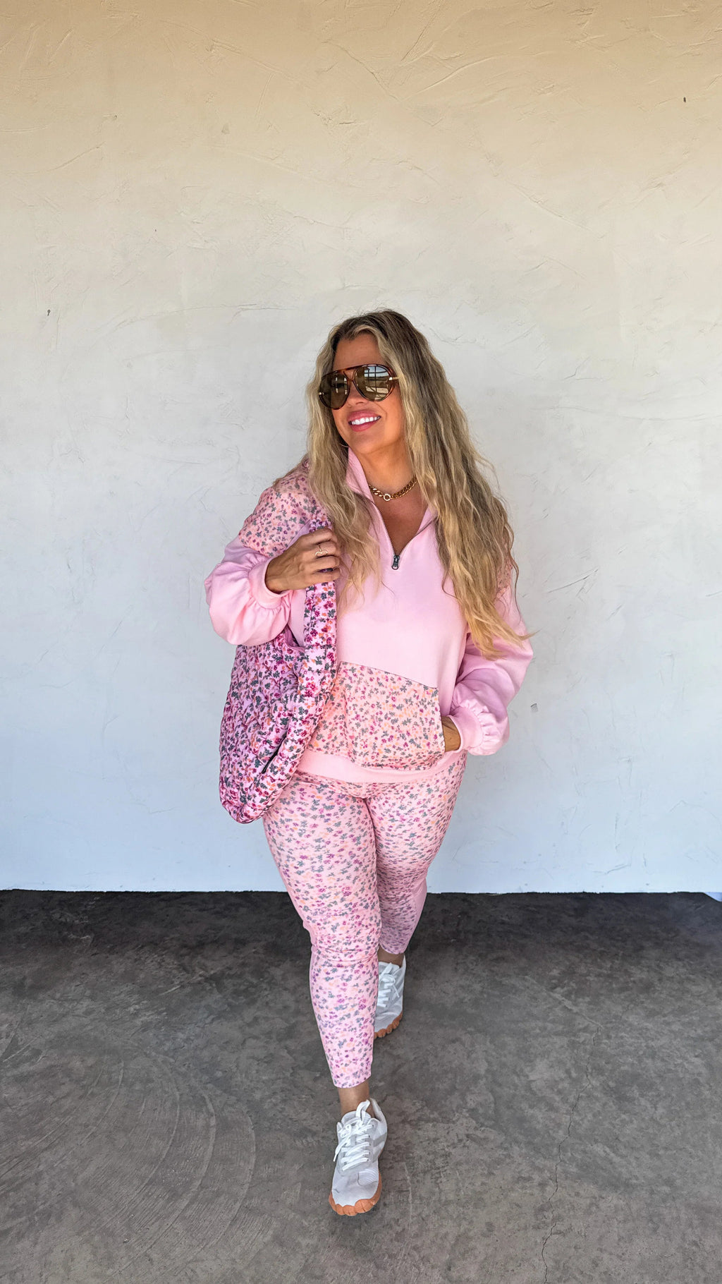 Woman in a pink floral tracksuit standing against a plain background